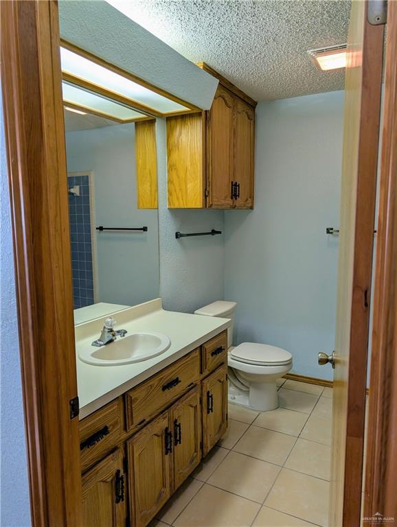 bathroom featuring toilet, vanity, tile patterned flooring, and a textured ceiling