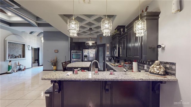 kitchen with coffered ceiling, appliances with stainless steel finishes, decorative light fixtures, kitchen peninsula, and a breakfast bar area