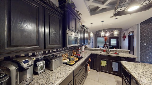 kitchen featuring light tile patterned floors, dark brown cabinets, coffered ceiling, and sink