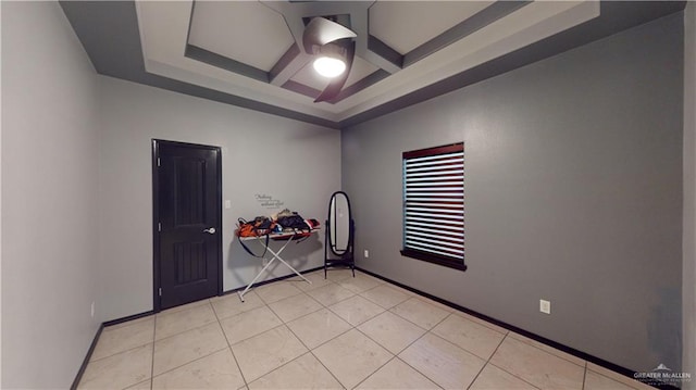 tiled empty room with beam ceiling, a raised ceiling, and coffered ceiling