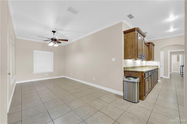 kitchen featuring light stone counters, ceiling fan, light tile patterned flooring, and crown molding