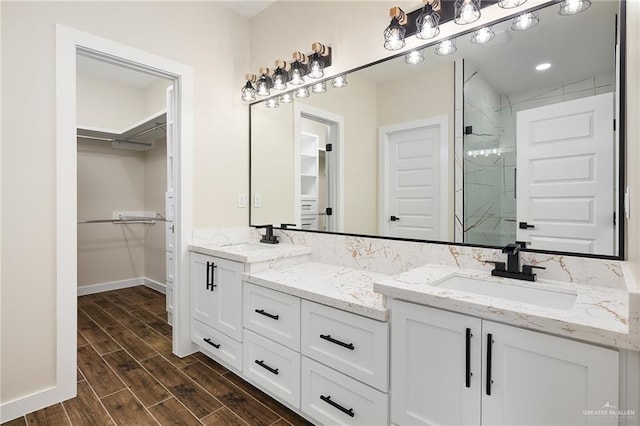 15439 E Davis Rd, Edinburg, TX 78542 - bathroom with double vanity, a marble finish shower, a walk in closet, and wood finished floors