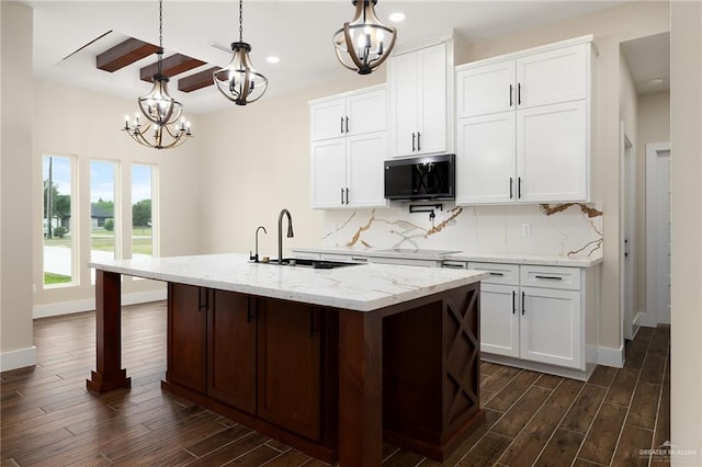 15439 E Davis Rd, Edinburg, TX 78542 - kitchen featuring a sink, a chandelier, dark wood-type flooring, tasteful backsplash, and a center island with sink