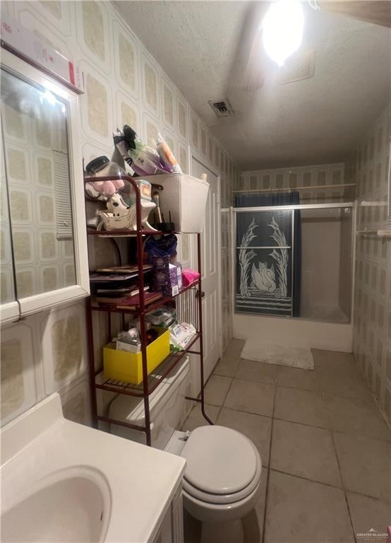 bathroom featuring tile patterned flooring, vanity, toilet, and a textured ceiling