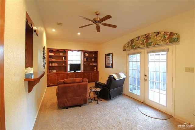 carpeted living room featuring built in shelves, french doors, ceiling fan, and a healthy amount of sunlight