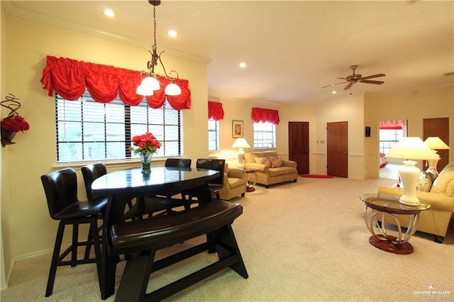 carpeted dining area with a wealth of natural light, ornamental molding, and ceiling fan