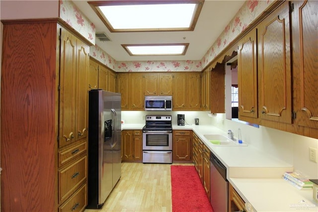 kitchen with appliances with stainless steel finishes, light hardwood / wood-style flooring, and sink