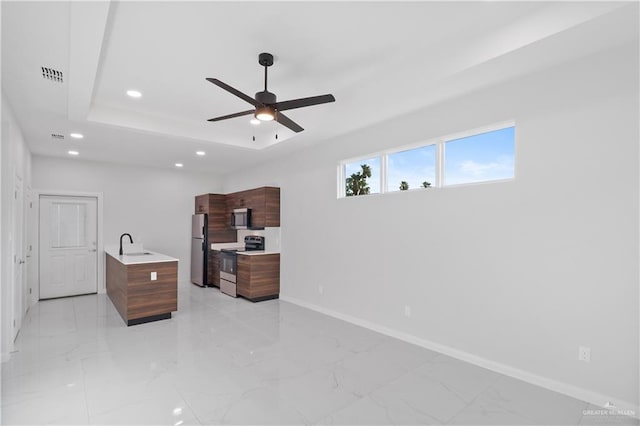 bedroom featuring stainless steel refrigerator, ceiling fan, a tray ceiling, and sink