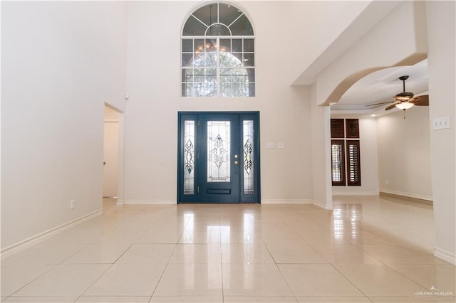 entryway featuring ceiling fan, a towering ceiling, and light tile patterned floors