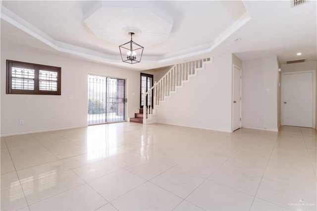 tiled foyer featuring a tray ceiling and an inviting chandelier