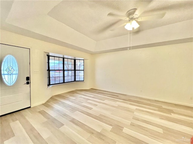 entryway with ceiling fan, a textured ceiling, a tray ceiling, and light hardwood / wood-style flooring