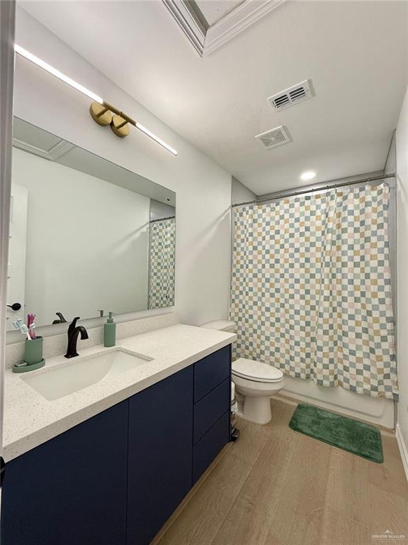 bathroom featuring hardwood / wood-style flooring, toilet, vanity, and a shower with shower curtain