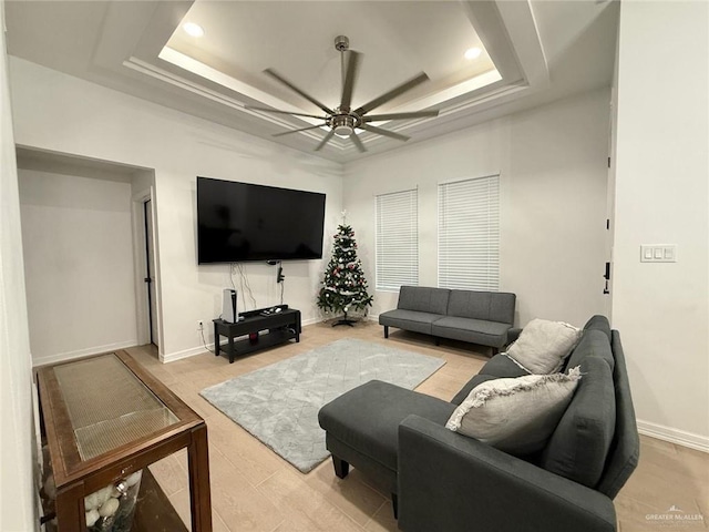 living room featuring a raised ceiling and ceiling fan