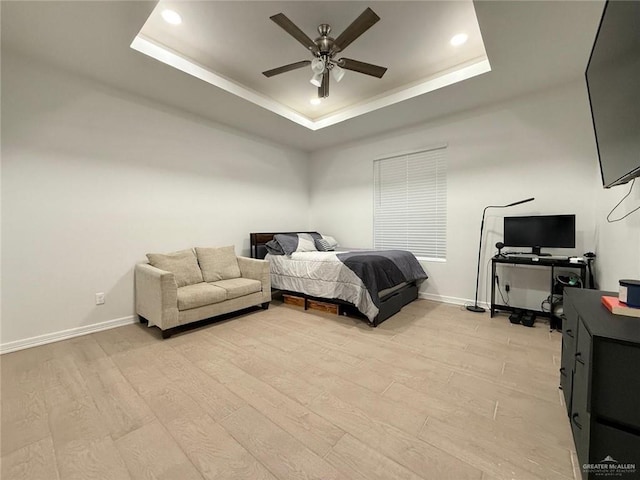 bedroom featuring ceiling fan, a tray ceiling, and light hardwood / wood-style floors