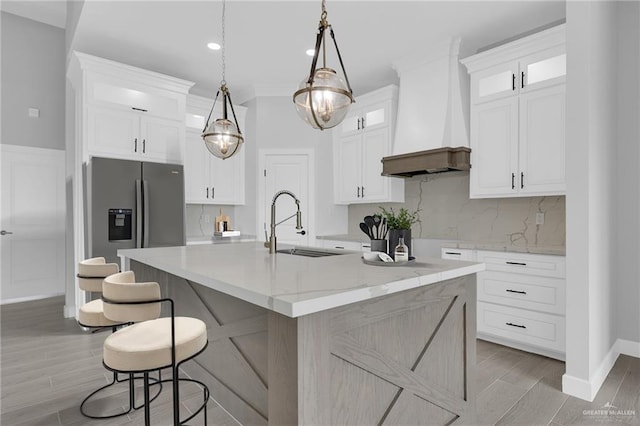 1104 Azalea Ave, Mission, TX 78573 - kitchen with custom exhaust hood, stainless steel refrigerator with ice dispenser, white cabinets, a kitchen island with sink, and backsplash
