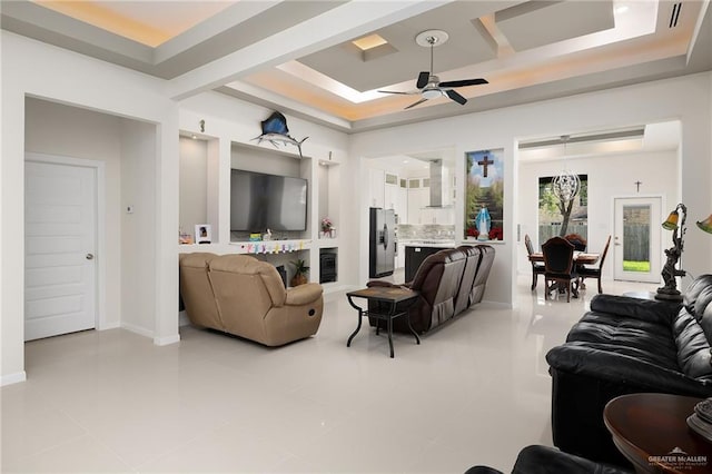 living room featuring baseboards, ceiling fan, light tile patterned floors, and a raised ceiling