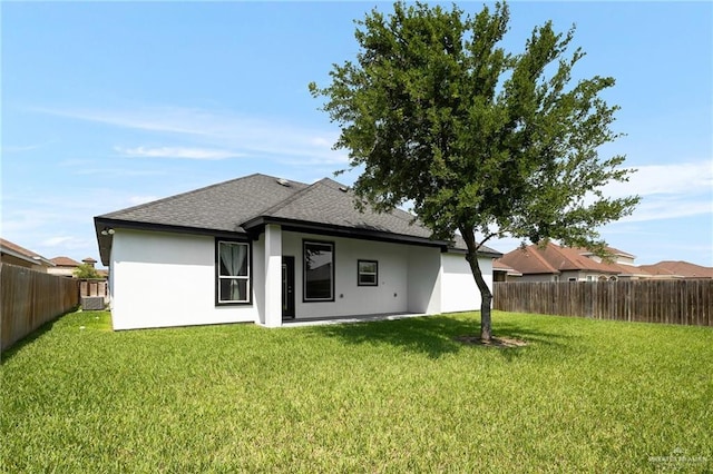 rear view of property featuring a fenced backyard, a lawn, stucco siding, and roof with shingles