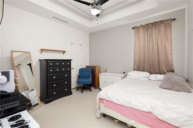 bedroom with a tray ceiling, visible vents, and ceiling fan