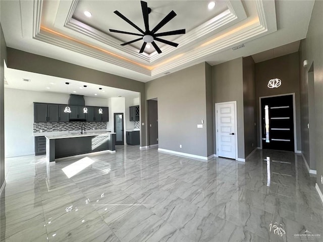 unfurnished living room featuring ceiling fan, a tray ceiling, and crown molding