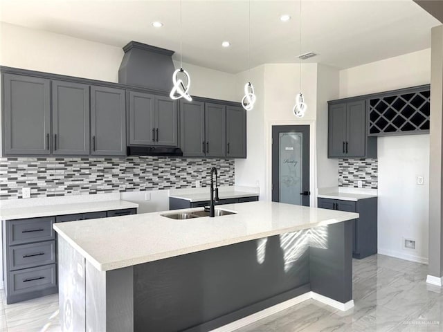 kitchen with decorative backsplash, sink, a center island with sink, and decorative light fixtures