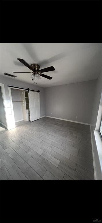 2201 S Jackson Rd Unit J11, Pharr, TX 78577 - unfurnished bedroom featuring a barn door, baseboards, wood finished floors, and visible vents