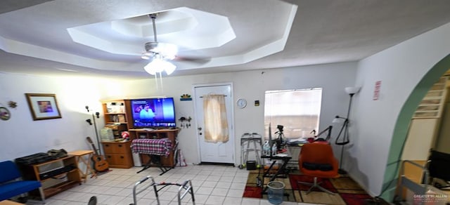 living room with a tray ceiling and ceiling fan