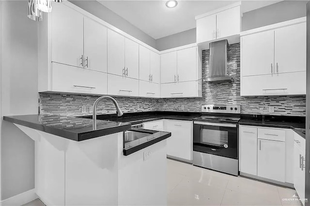 kitchen with electric range, white cabinets, wall chimney range hood, and kitchen peninsula