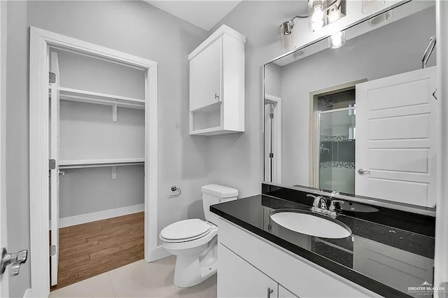 bathroom featuring tile patterned flooring, vanity, a shower with shower door, and toilet