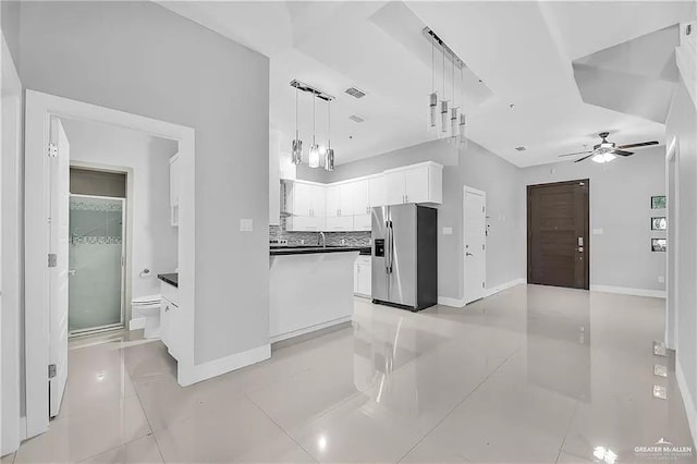 kitchen with decorative backsplash, stainless steel fridge, ceiling fan, white cabinets, and hanging light fixtures