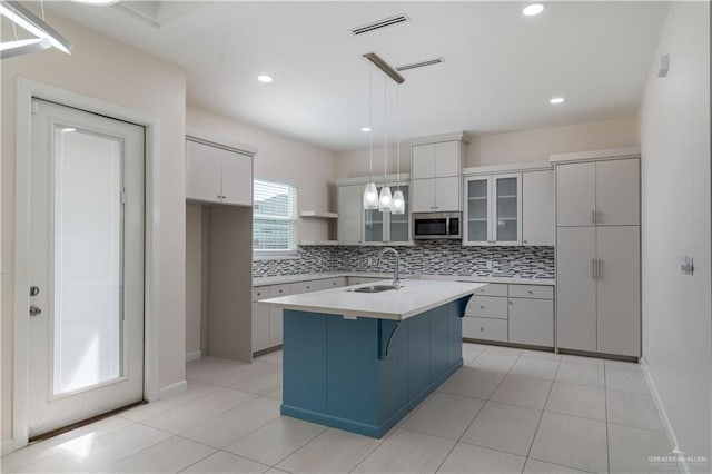 kitchen featuring sink, pendant lighting, a kitchen bar, decorative backsplash, and a center island with sink