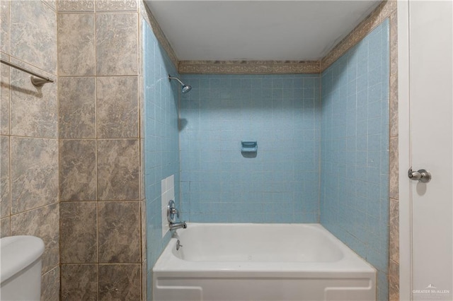 bathroom featuring tiled shower / bath combo and toilet