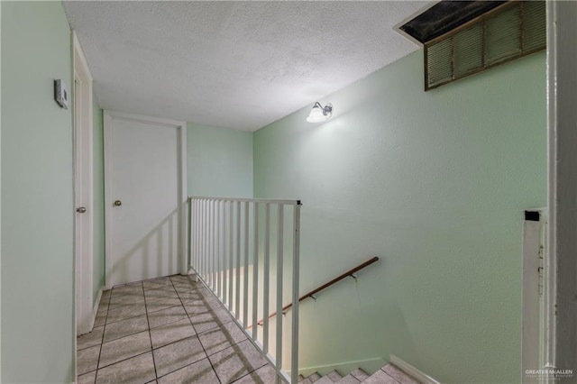 stairs featuring tile patterned flooring and a textured ceiling