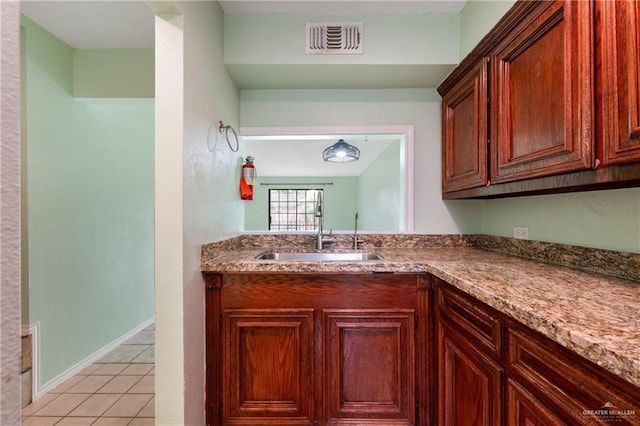 kitchen with sink, light tile patterned floors, and stone counters