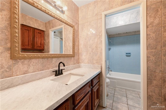 full bathroom featuring tile patterned flooring, tile walls, vanity, toilet, and tiled shower / bath