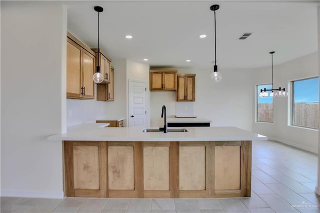 1502 Stirrup Cir, San Benito, TX 78586 - kitchen with a sink, a peninsula, recessed lighting, decorative light fixtures, and light countertops