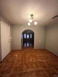 entrance foyer featuring arched walkways, visible vents, and a notable chandelier