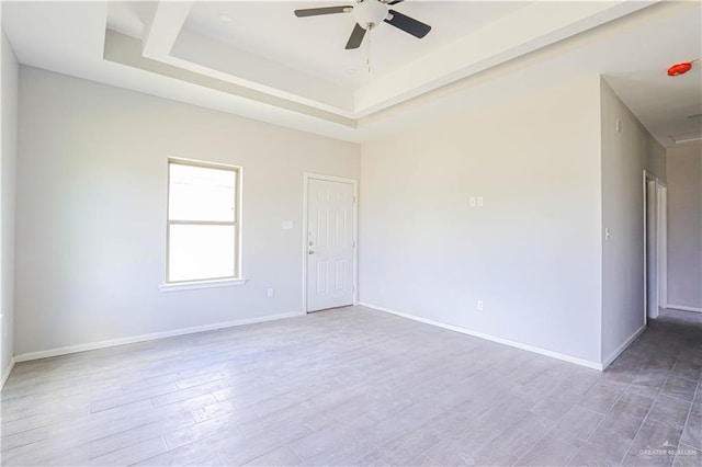 unfurnished room featuring hardwood / wood-style floors, ceiling fan, and a raised ceiling