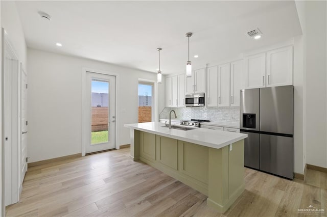 1214 N Lincoln Ave, San Juan, TX 78589 - kitchen featuring stainless steel appliances, a sink, backsplash, light wood-style flooring, and a kitchen island with sink
