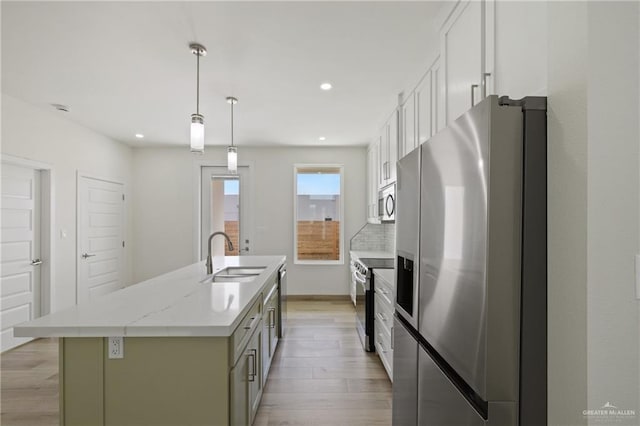 1214 N Lincoln Ave, San Juan, TX 78589 - kitchen featuring appliances with stainless steel finishes, a sink, light wood-style floors, a kitchen island with sink, and white cabinets
