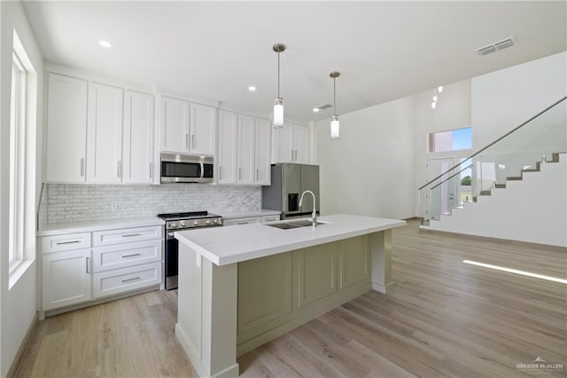 1214 N Lincoln Ave, San Juan, TX 78589 - kitchen with stainless steel appliances, backsplash, a sink, light wood-style floors, and an island with sink