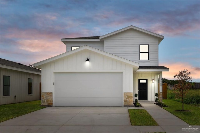 view of front of home featuring stone siding, board and batten siding, a garage, and driveway