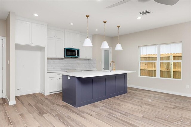 3409 Emma Dr, Weslaco, TX 78596 - kitchen with white cabinetry, decorative backsplash, baseboards, and light wood-type flooring