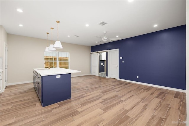 3409 Emma Dr, Weslaco, TX 78596 - kitchen featuring light countertops, light wood-type flooring, blue cabinetry, and a sink