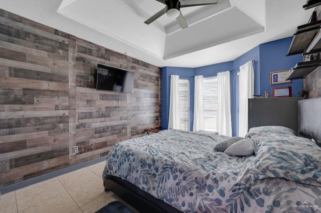 3908 Hill Crest Dr, Mission, TX 78573 - bedroom featuring a tray ceiling, wood walls, tile patterned floors, and a ceiling fan