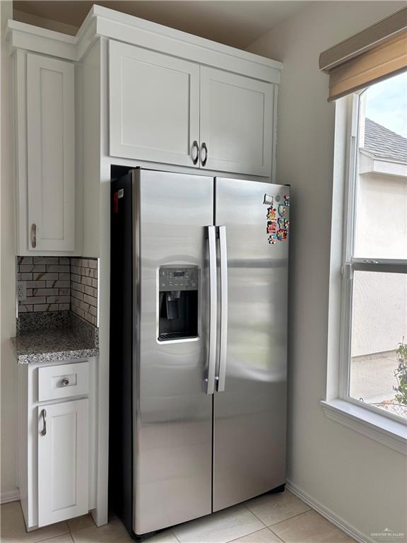 kitchen with tasteful backsplash, stainless steel fridge, and white cabinets