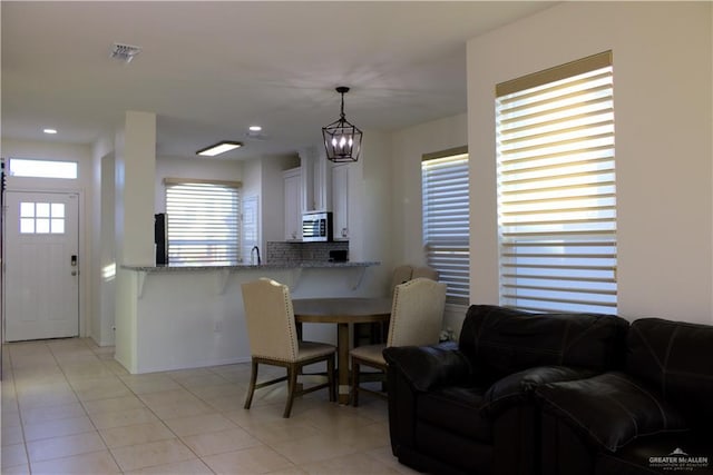 dining space featuring light tile patterned floors, a chandelier, sink, and a wealth of natural light