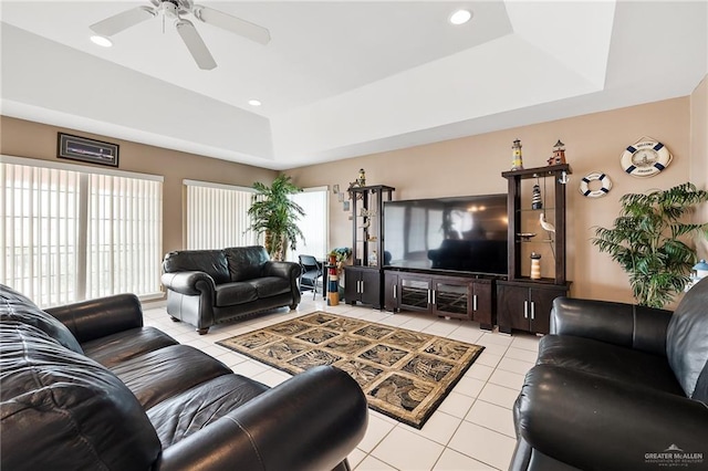 living room featuring a tray ceiling, ceiling fan, and light tile patterned floors