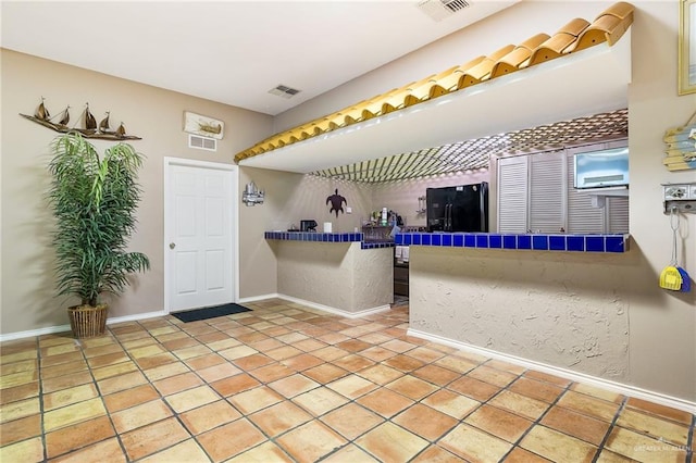 interior space featuring tile countertops, black fridge, and light tile patterned floors