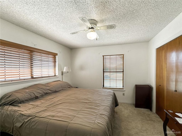 carpeted bedroom featuring a textured ceiling, a closet, and ceiling fan