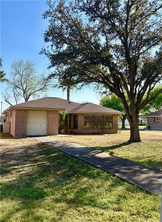 ranch-style home with brick siding, driveway, a front yard, and a garage